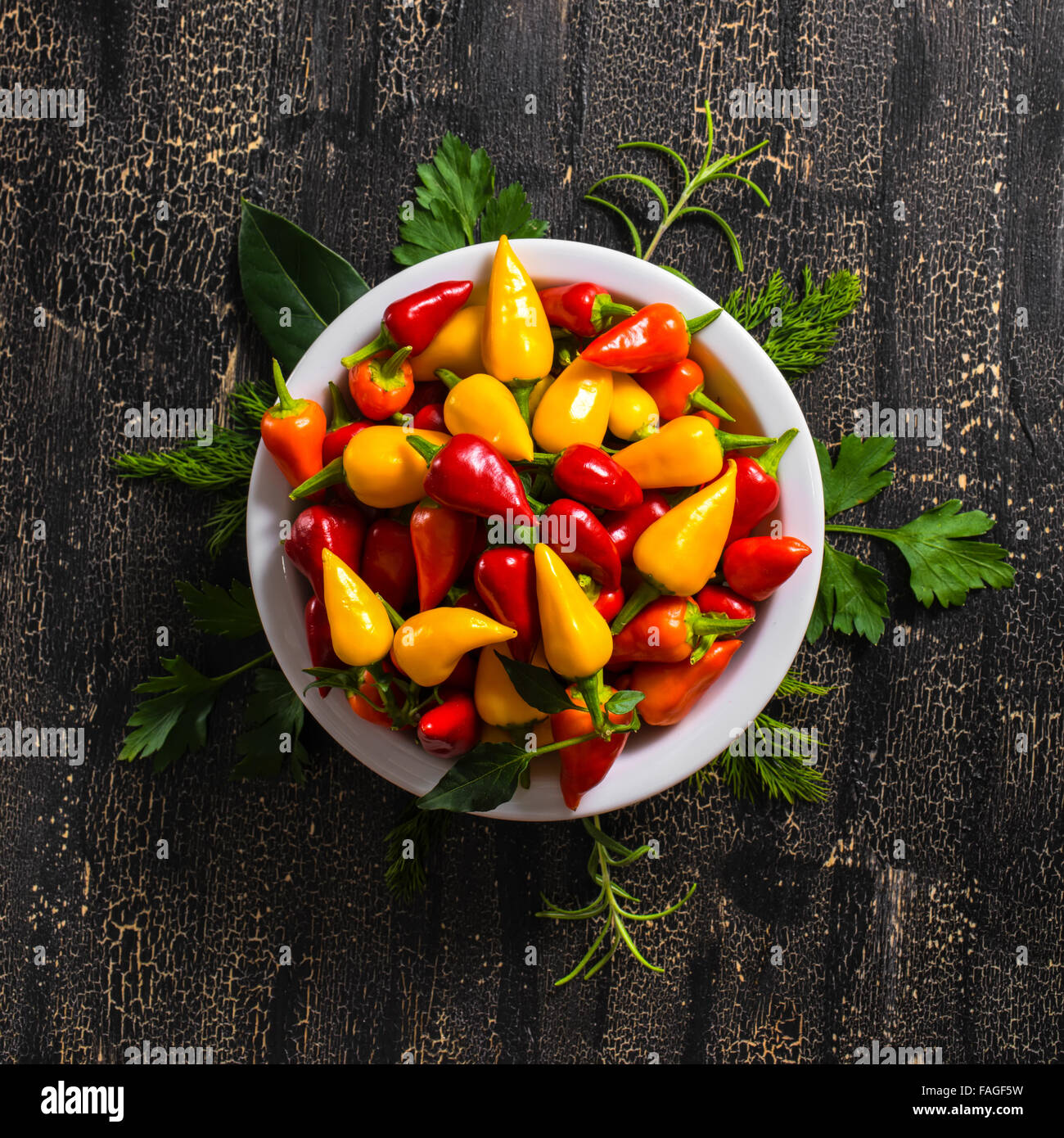Vue du haut de la plaque à l'orange, rouge et jaune Hot Chili Peppers, de verdure sur fond noir des fissures, Close up Banque D'Images
