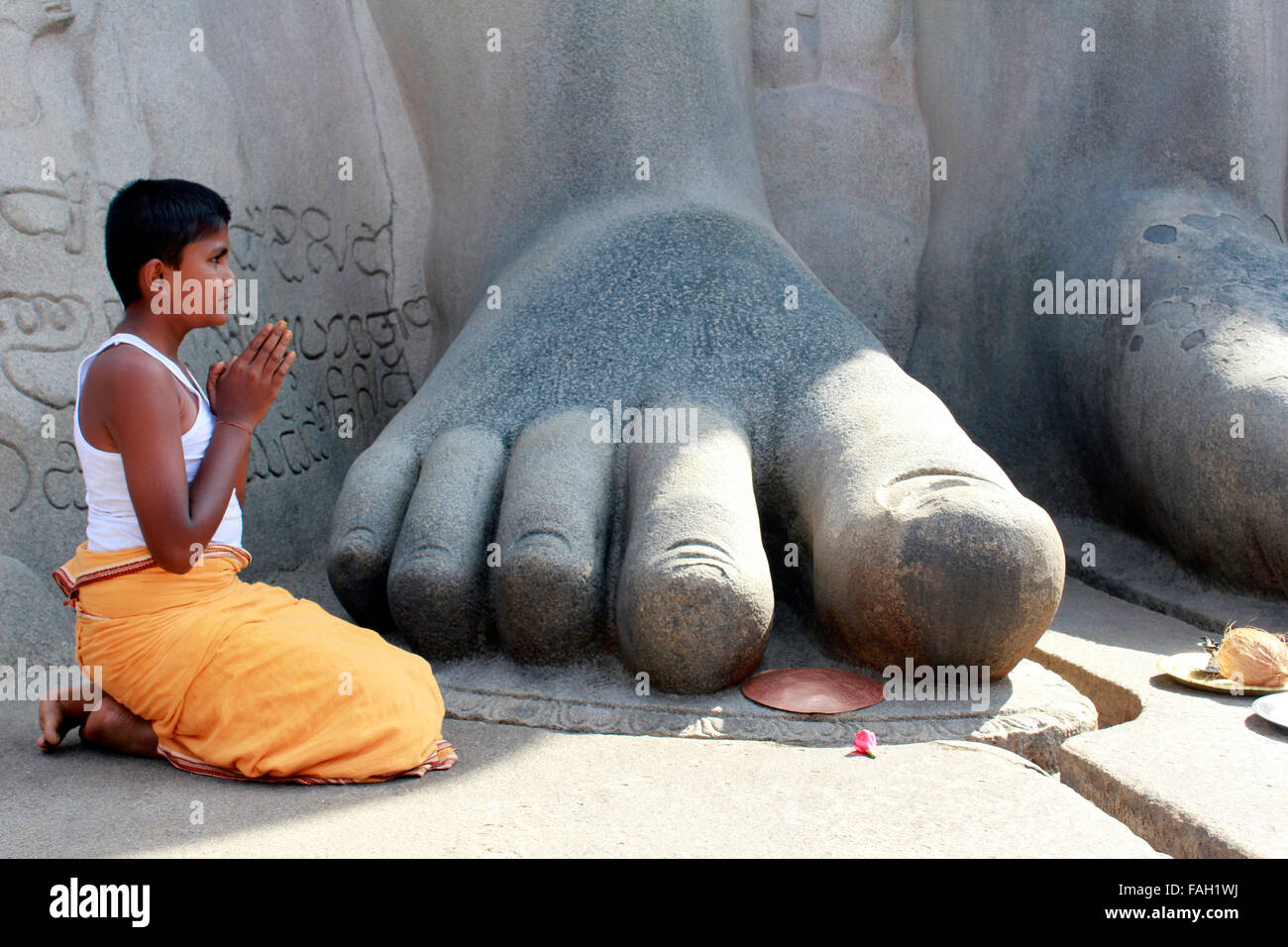 Un jeune prêtre prosterné aux pieds de Gommateshwara bahubali à Shravanabelagola Hassan dans le district de Karnataka, Inde Banque D'Images