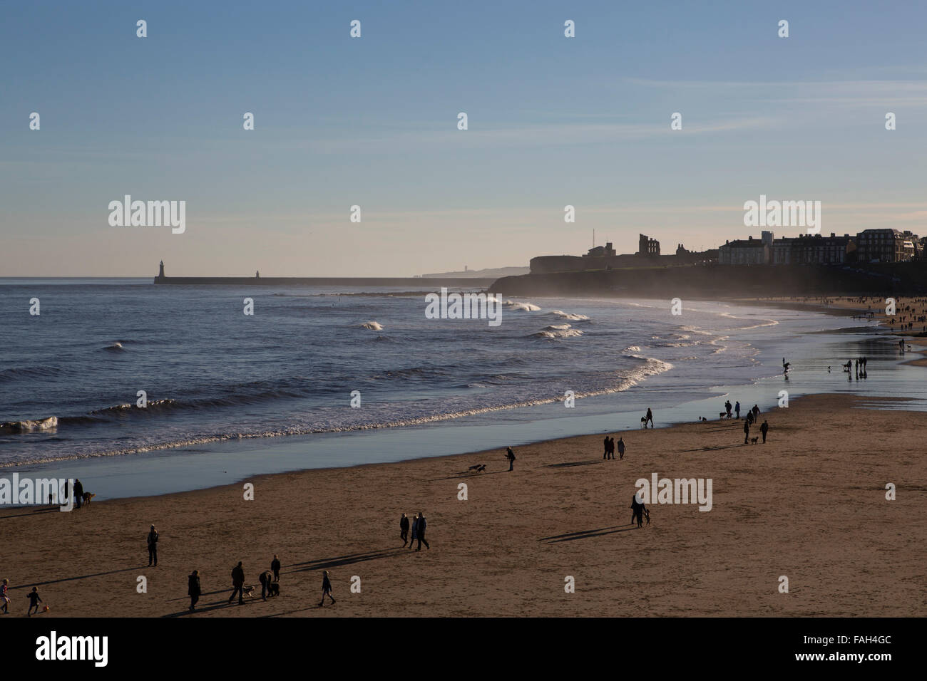 Les gens qui marchent sur la plage de Tynemouth, dans le nord-est de l'Angleterre. Tynemouth Pier juste dans la mer du Nord. Banque D'Images