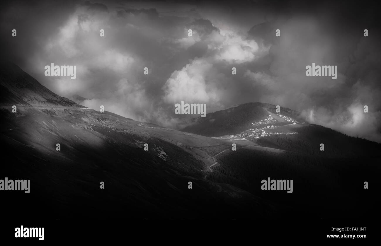 Grand paysage de montagne avec un village au loin, dans une interprétation en noir et blanc Banque D'Images