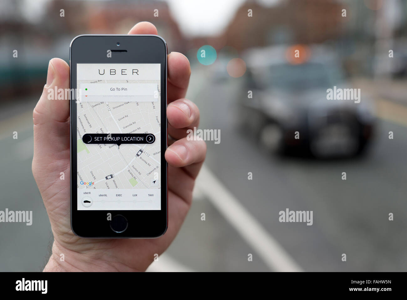Un homme utilise l'application pour smartphone taxi Uber, tandis que s'élevait à une station de taxi (usage éditorial uniquement) Banque D'Images