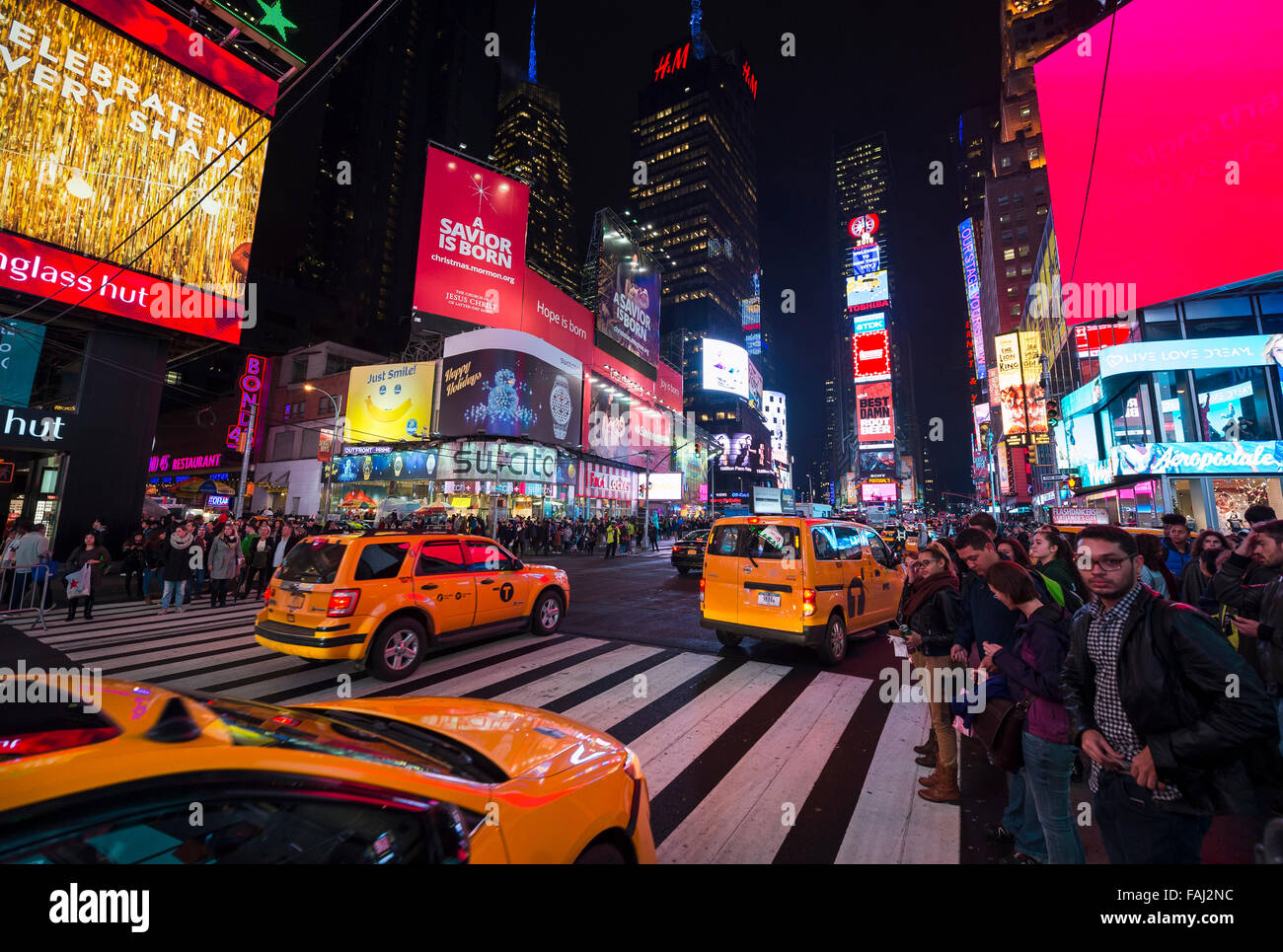 La VILLE DE NEW YORK, USA - Le 22 décembre 2015 : le jaune des taxis de New York pass collecte des foules sous l'éclairage intense de Times Square. Banque D'Images