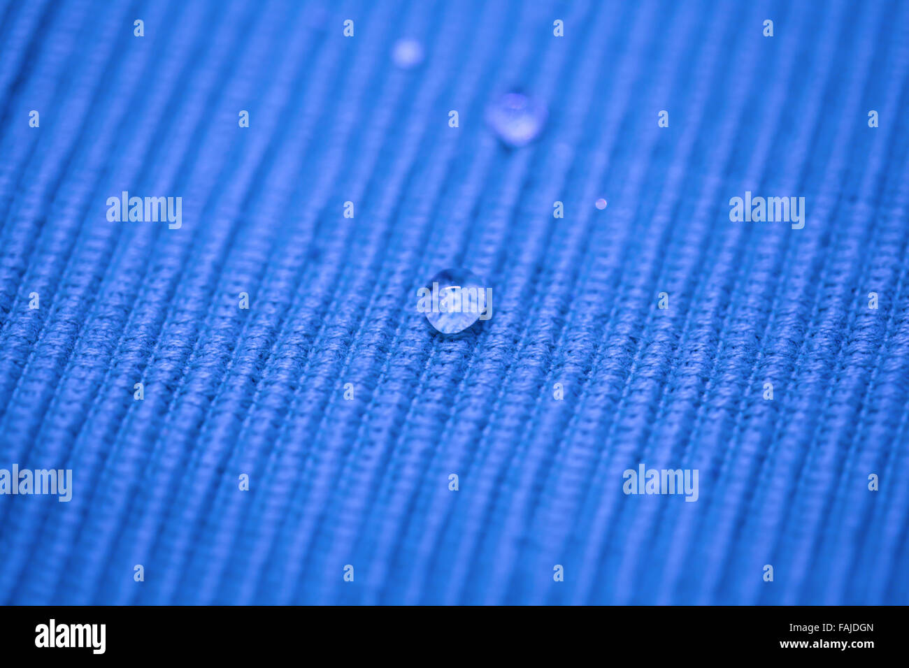 Goutte d'eau macro sur un tissu bleu Banque D'Images