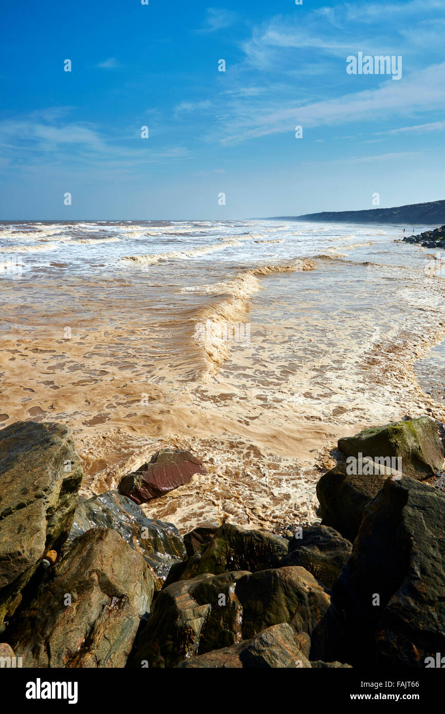 Une légère brise de mer agitée dans de petites vagues contre les rochers sur la plage Mappleton Banque D'Images