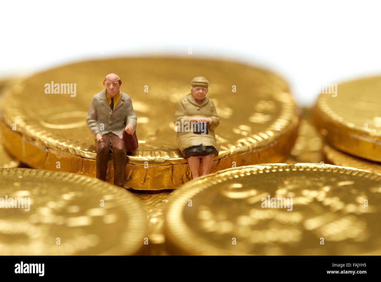 Les retraités miniature assis sur un tas de pièces en chocolat Banque D'Images