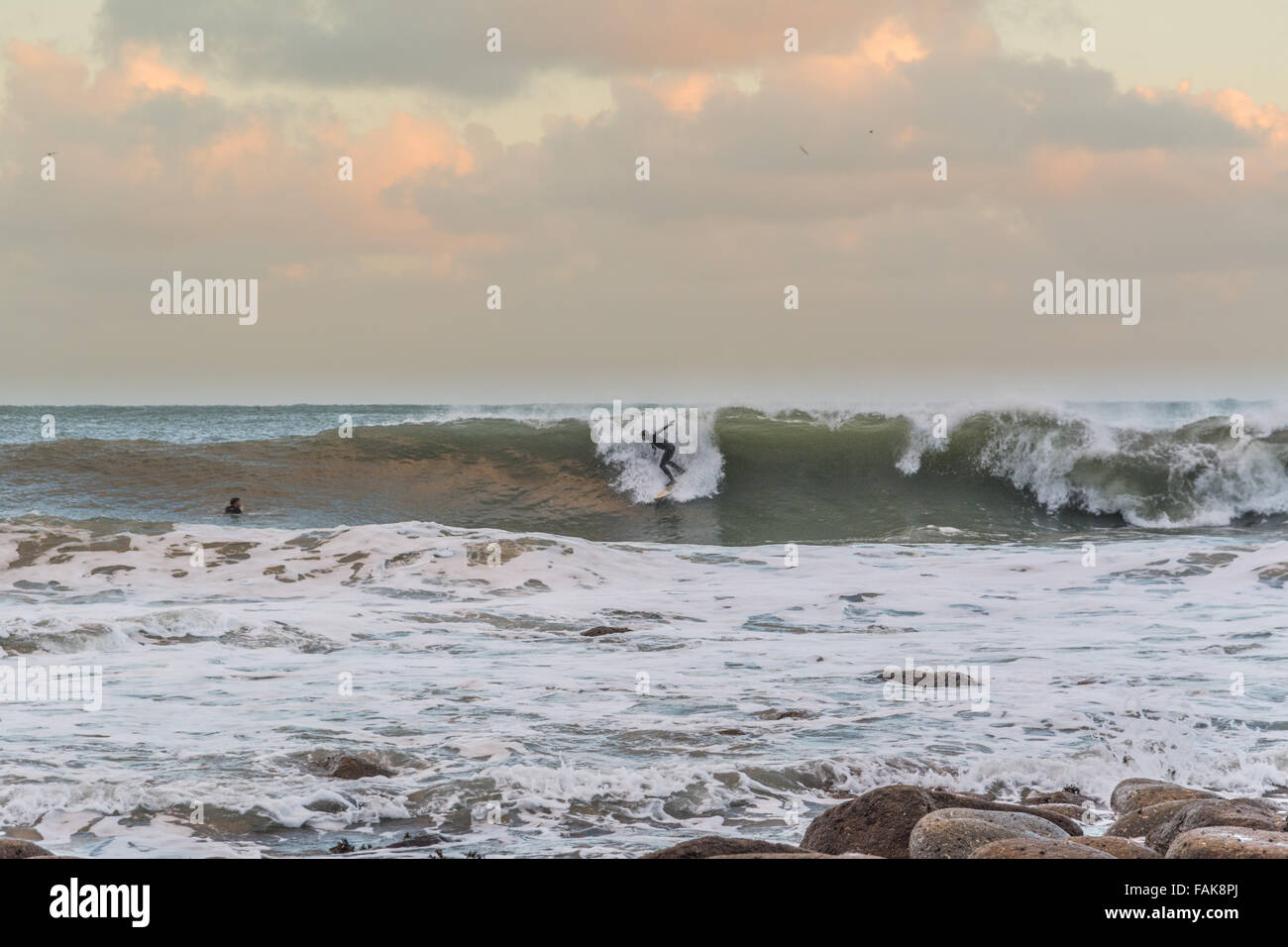 Mousehole, Cornwall, UK. Météo britannique. Le 31 décembre 2015. Surfers appréciant la queue du storm Frank, au coucher du soleil le soir du Nouvel an à Mousehole. Crédit : Simon Yates/Alamy Live News Banque D'Images