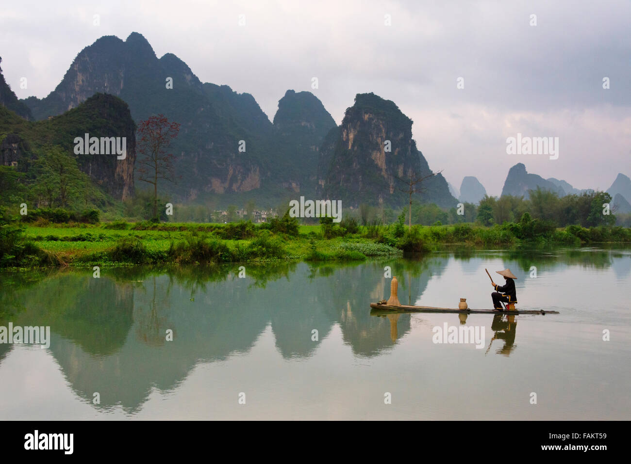 Pêcheur sur la rivière en radeau de bambou sur les collines karstiques Mingshi avec au coucher du soleil, dans la province de Guangxi, Chine Banque D'Images