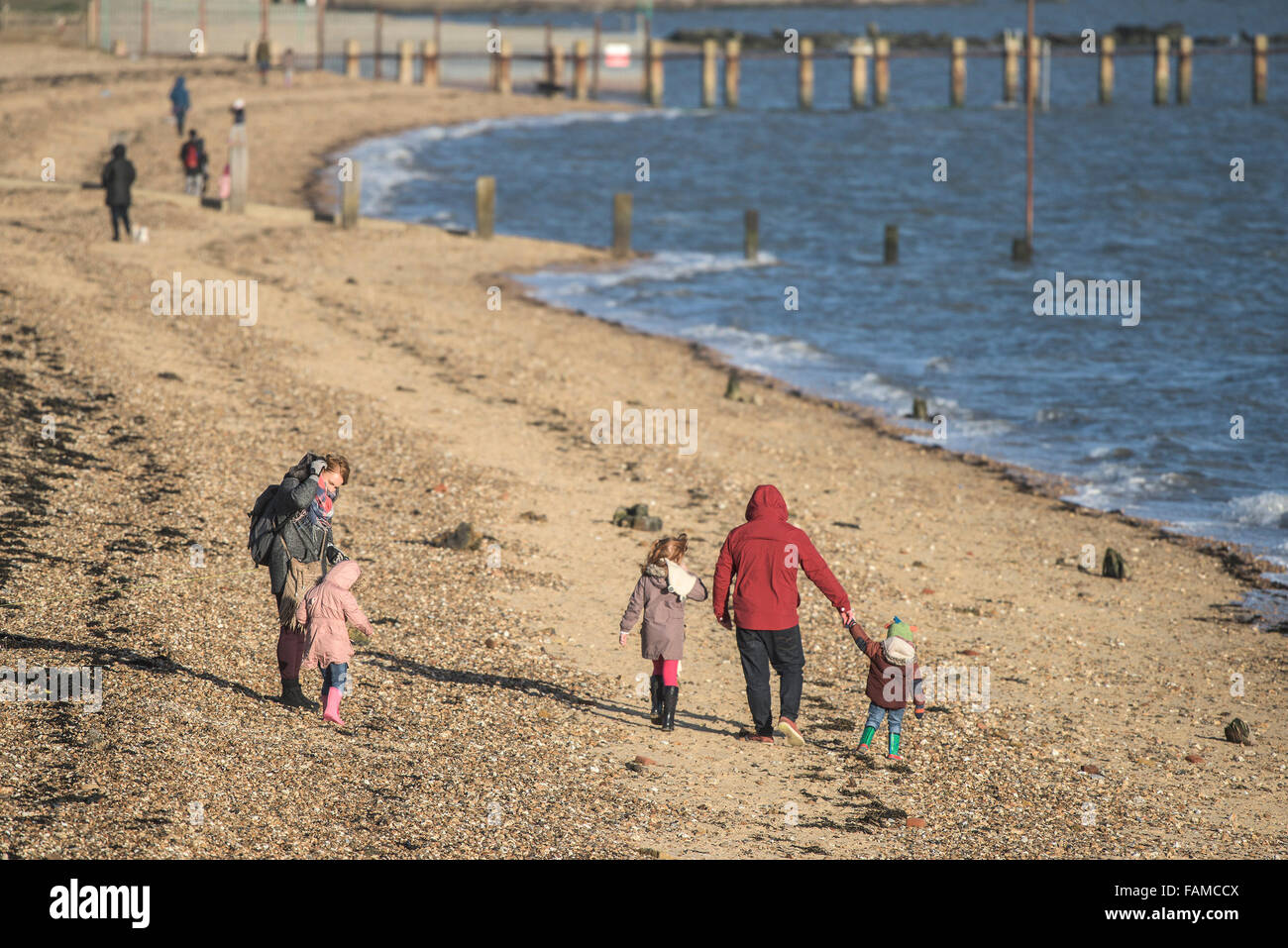 Une famille marchant le long de la plage de l'Est à Shoeburyness, Essex, Royaume-Uni. Banque D'Images