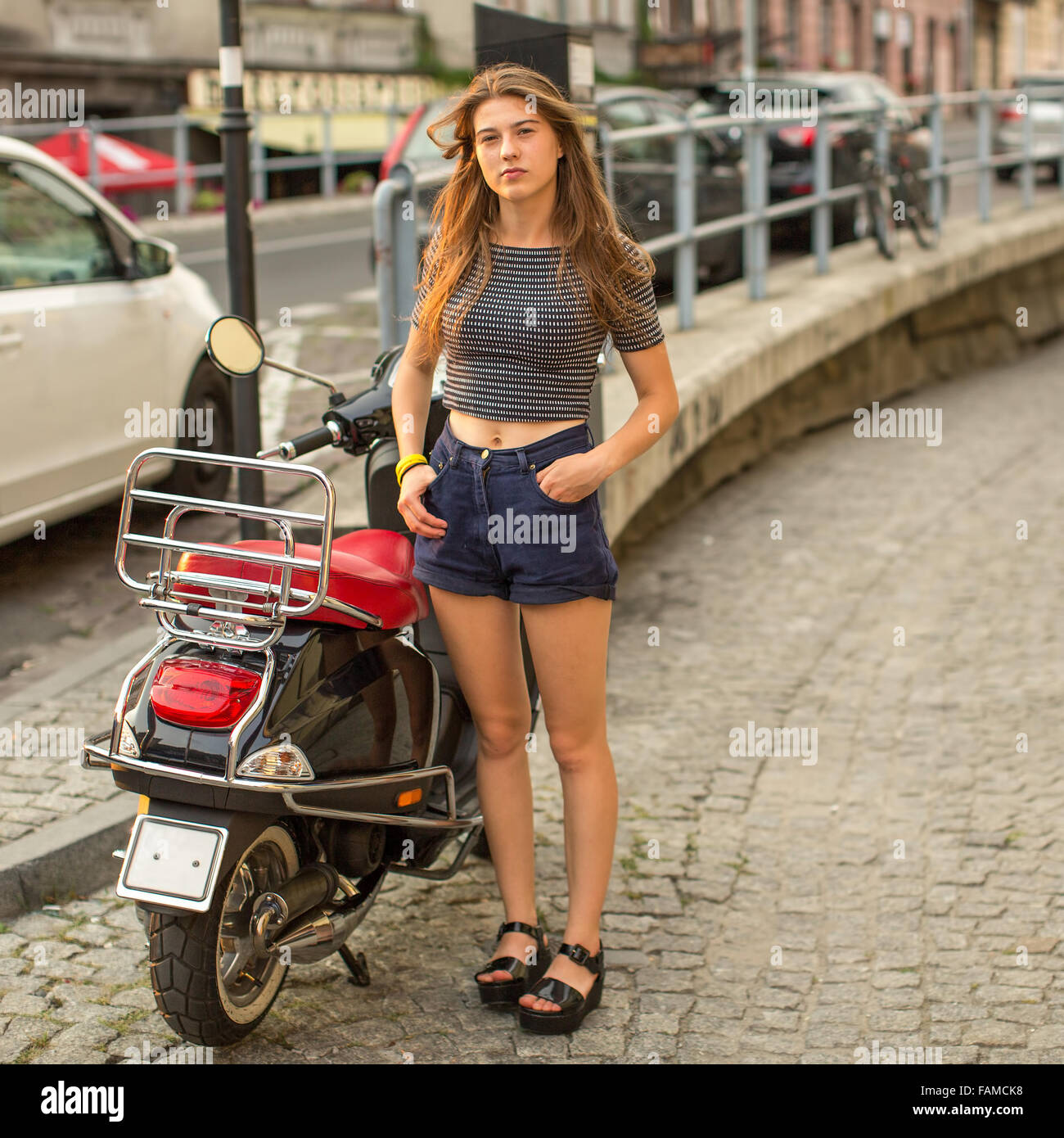 Jolie jeune fille avec un scooter dans la vieille ville. Banque D'Images