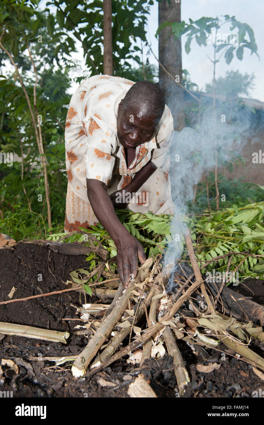 Femme préparant un foyer pour fabriquer du charbon de bois à vendre au marché. Au Kenya. Banque D'Images