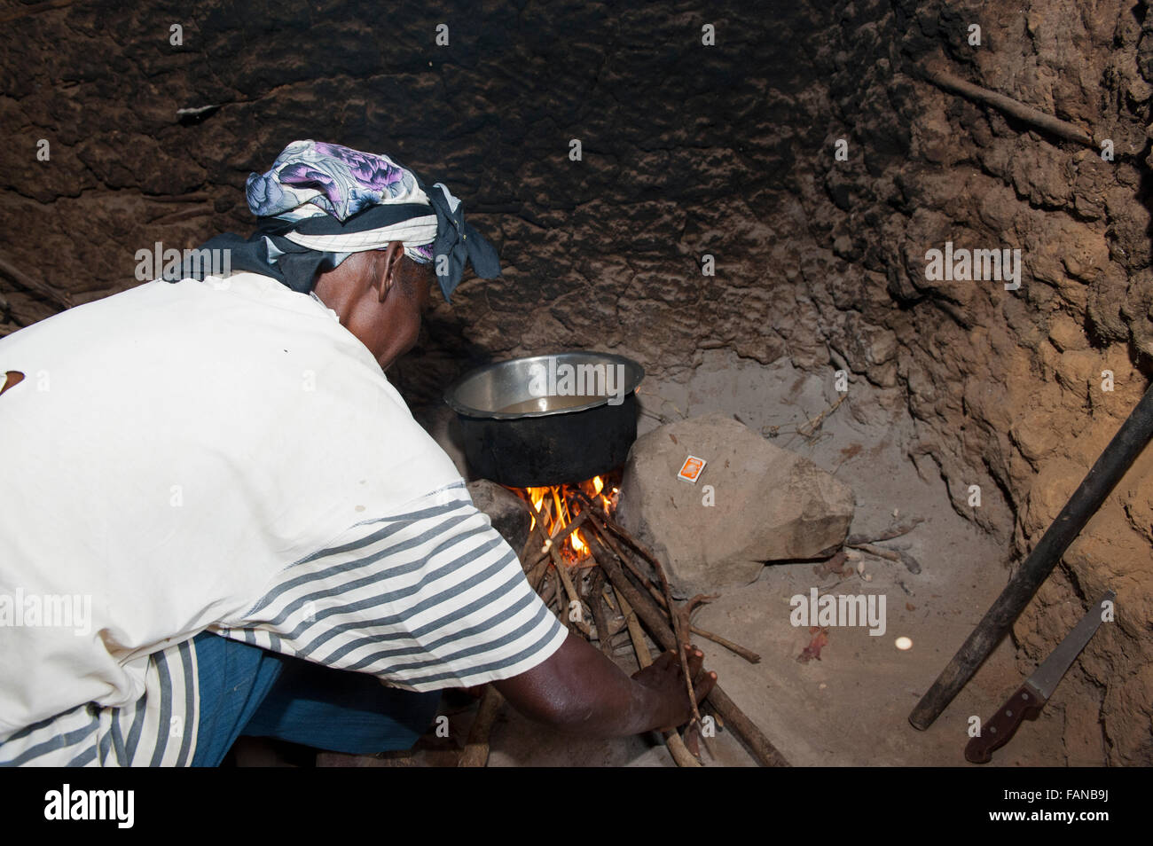 L'éclairage d'un feu ouvert femme cuisinière dans une cuisine pour cuisiner repas en famille. Au Kenya. Banque D'Images