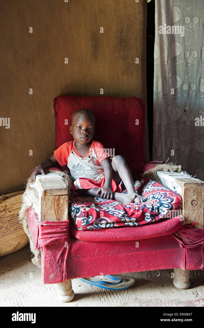 Un jeune enfant africain se détendre sur un fauteuil dans sa maison. Kenya Banque D'Images