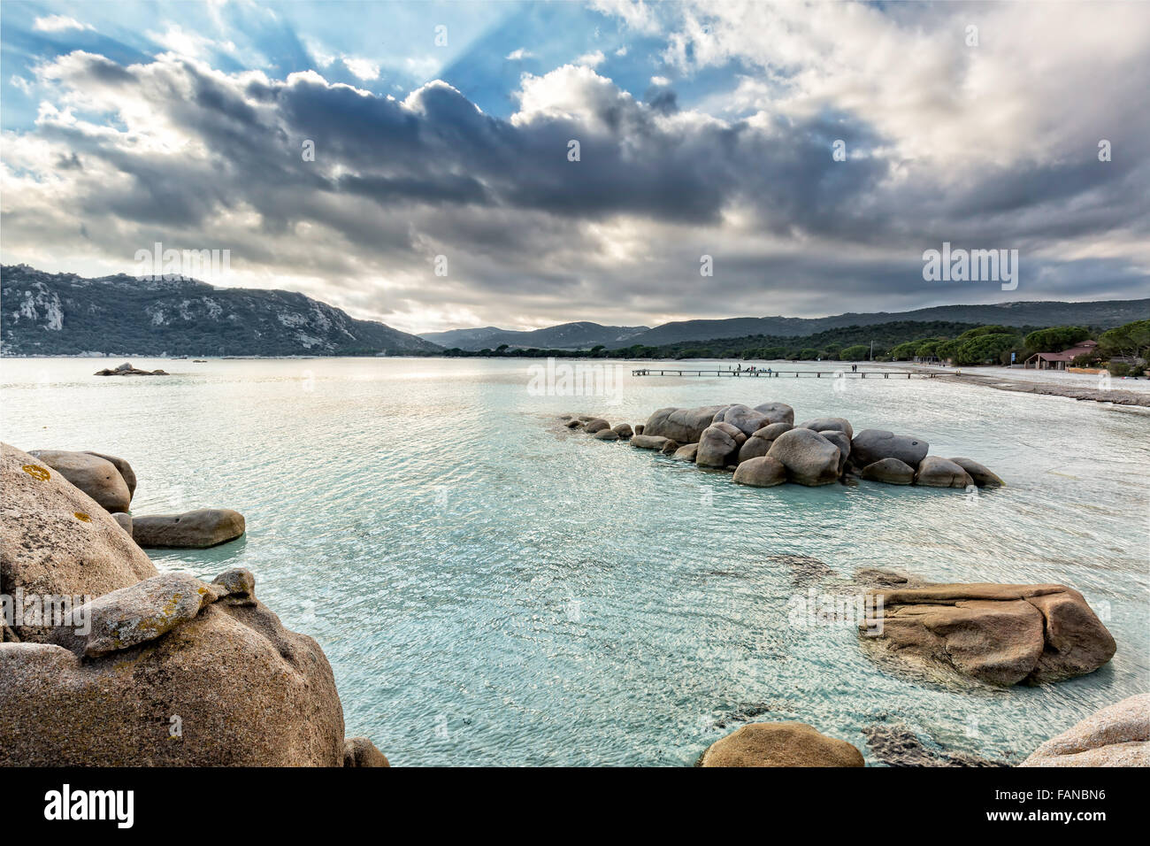 Les Roches et rochers dans une mer turquoise avec une jetée en arrière-plan et ciel nuageux, la plage de Santa Giulia en Corse Banque D'Images