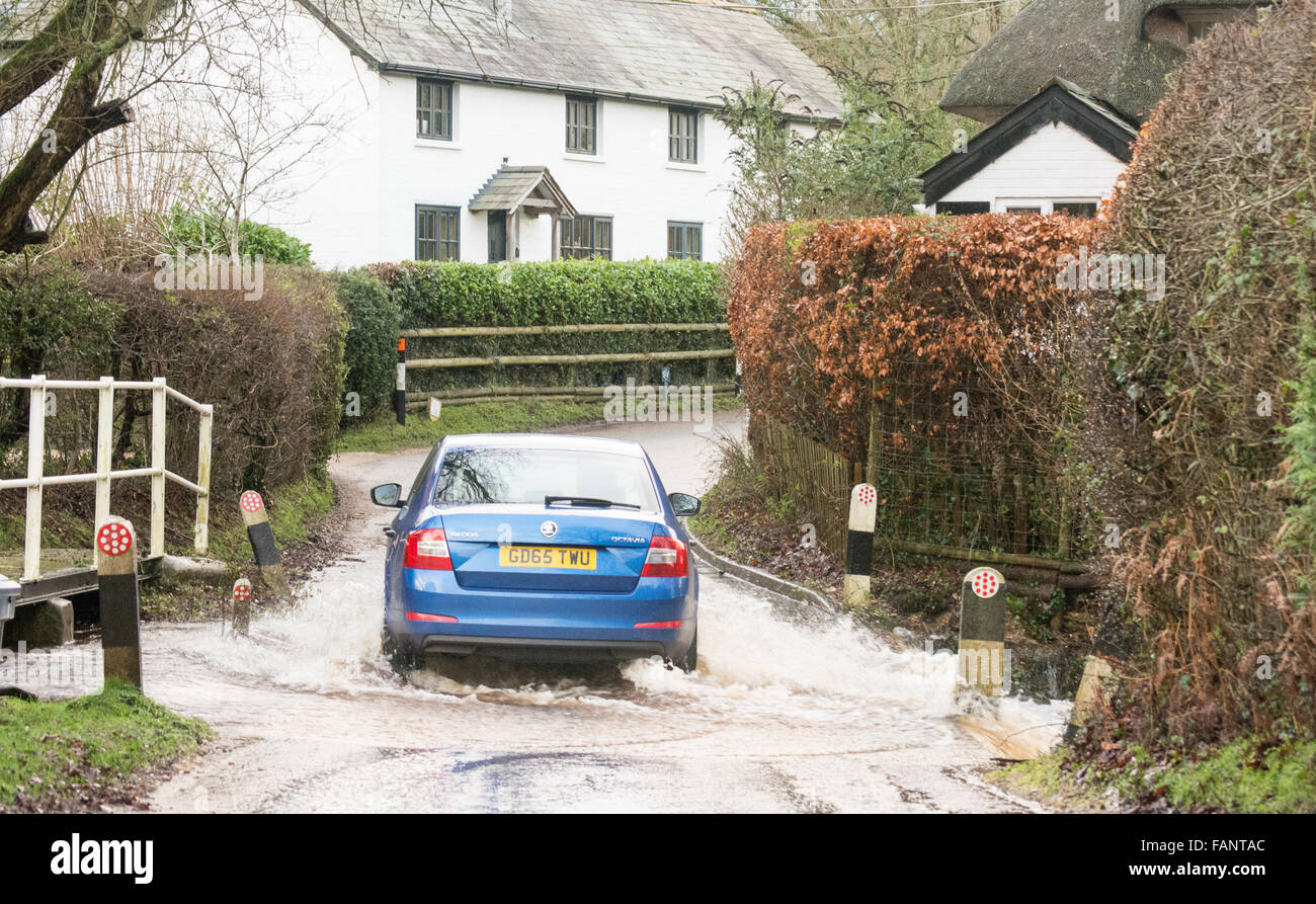 Voiture conduite à travers l'eau dans une ford inondée sur une route de campagne après de fortes pluies dans la Nouvelle forêt, Hampshire, Angleterre, Royaume-Uni Banque D'Images