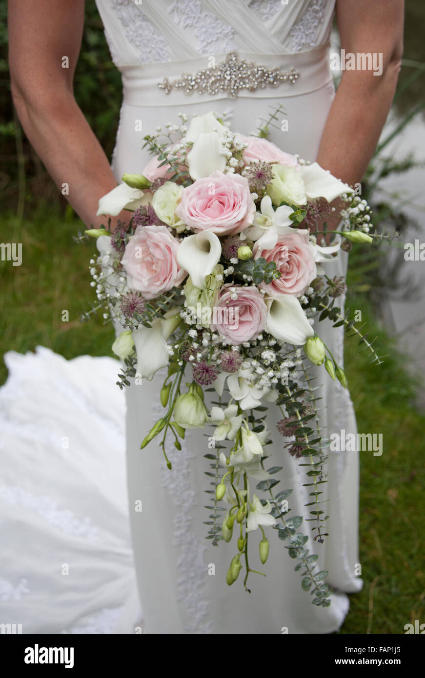 Bouquet de mariage, qui a eu lieu en face de sa robe de mariage, montrant  des roses rose et blanc avec cala lilies à un feuillage vert anglais country  wedding Photo Stock -