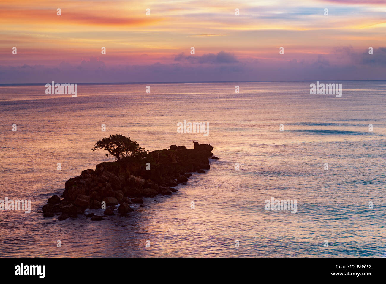 Dawn violet caraïbes au-dessus d'une petite île rocheuse avec un arbre isolé. Banque D'Images