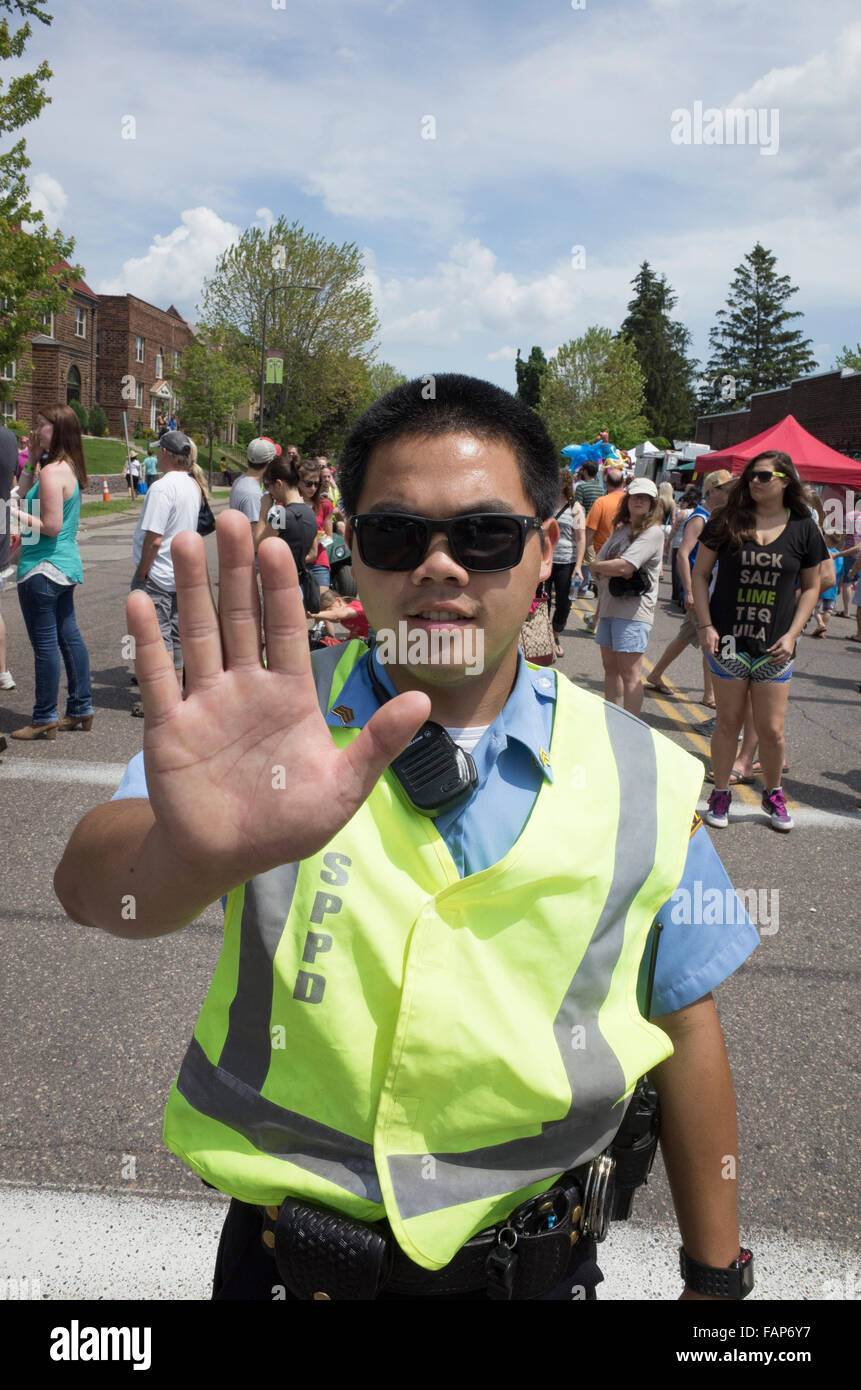 Young Asian American réserver policier holding hand jusqu'à arrêter le trafic. Grand Old jour Foire de rue. St Paul Minnesota MN USA Banque D'Images