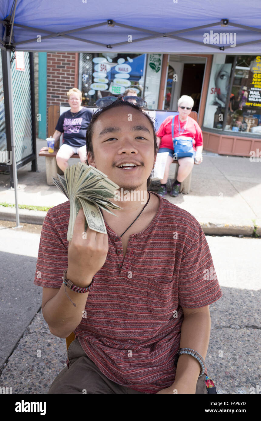 Jeune homme asiatique se retourne fièrement le wad d'argent à son stand de concession. Grand Old jour Foire de rue. St Paul Minnesota MN USA Banque D'Images