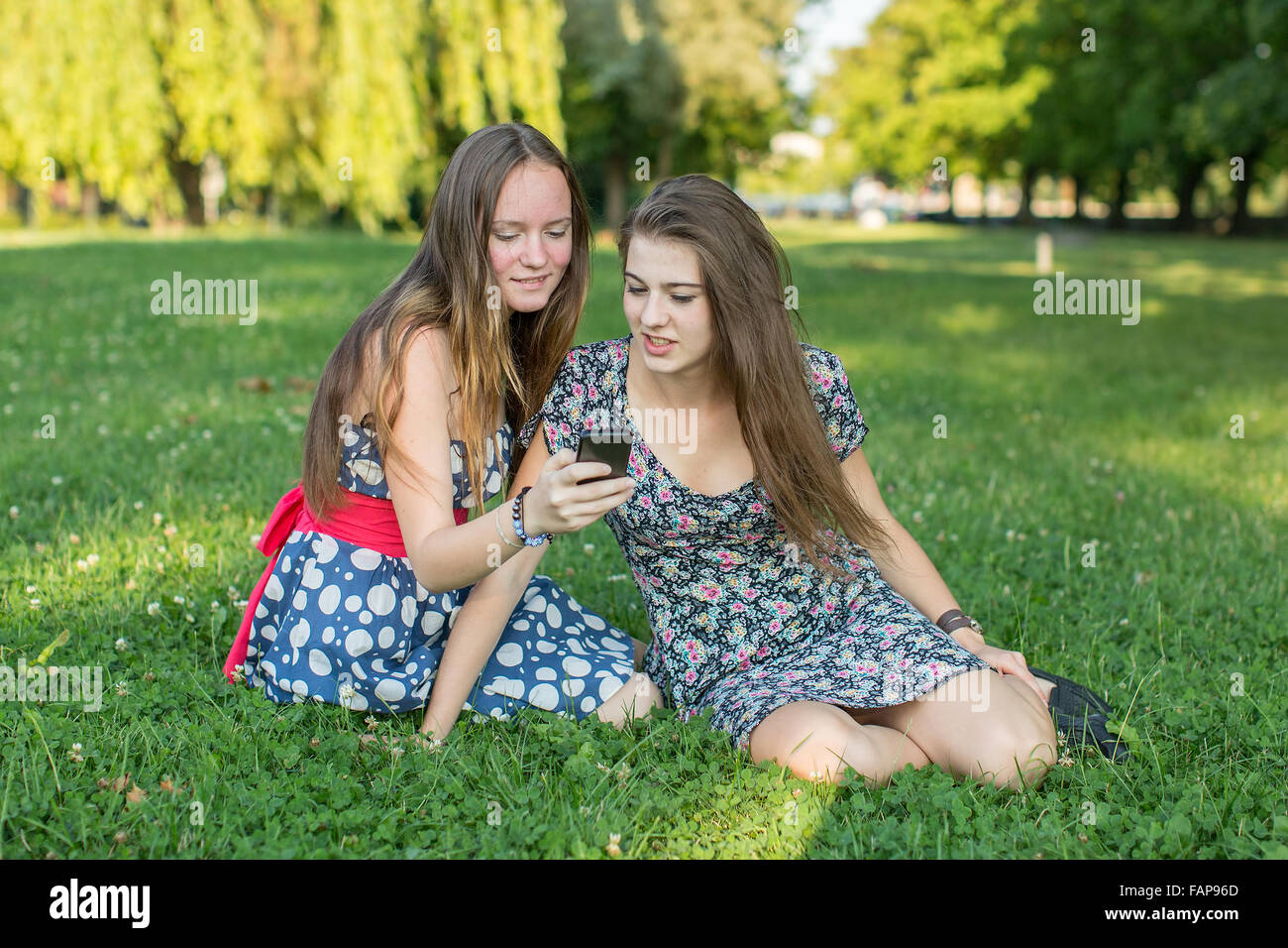 Deux copines assis dans une clairière ainsi utiliser un smartphone. Banque D'Images