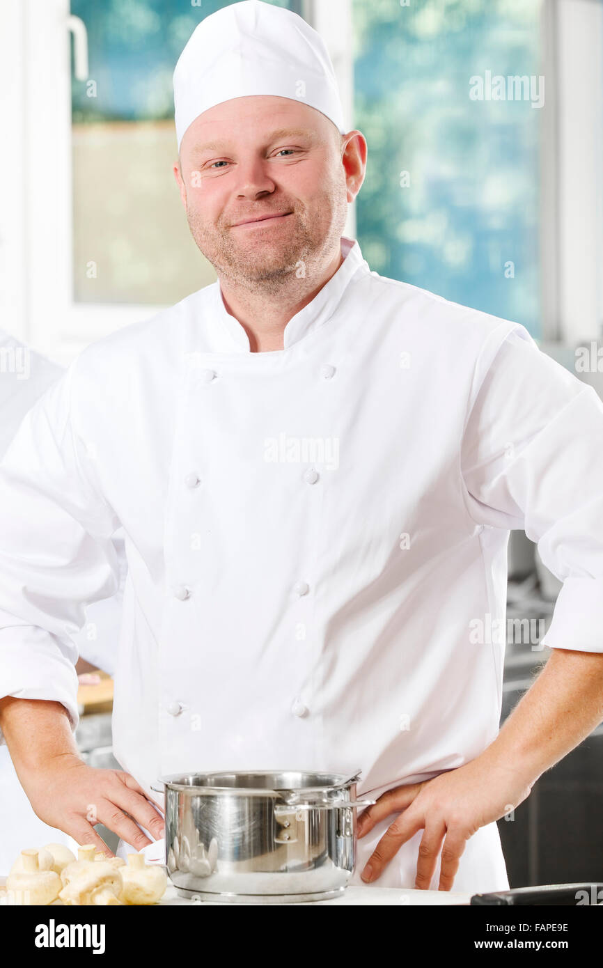 Confiant et souriant chef standing in grande cuisine Banque D'Images