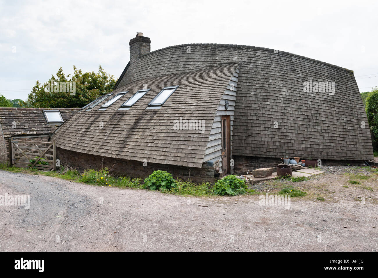 Herefordshire, UK. Une maison construite en bois, doublés, avec un toit incurvé en bois recouvert de bardeaux de cèdre Banque D'Images