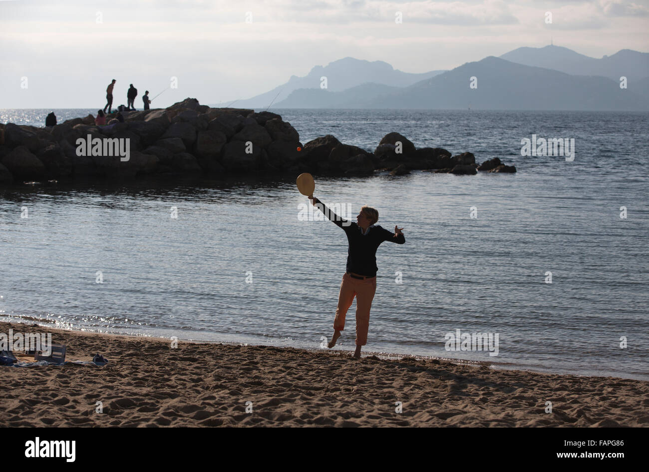 Les amateurs de soleil d'hiver bénéficiant d'une journée ensoleillée sur la Rviera beach, boulevard du Midi Jean Hibert, Cannes, Côte d'Azur, France Banque D'Images
