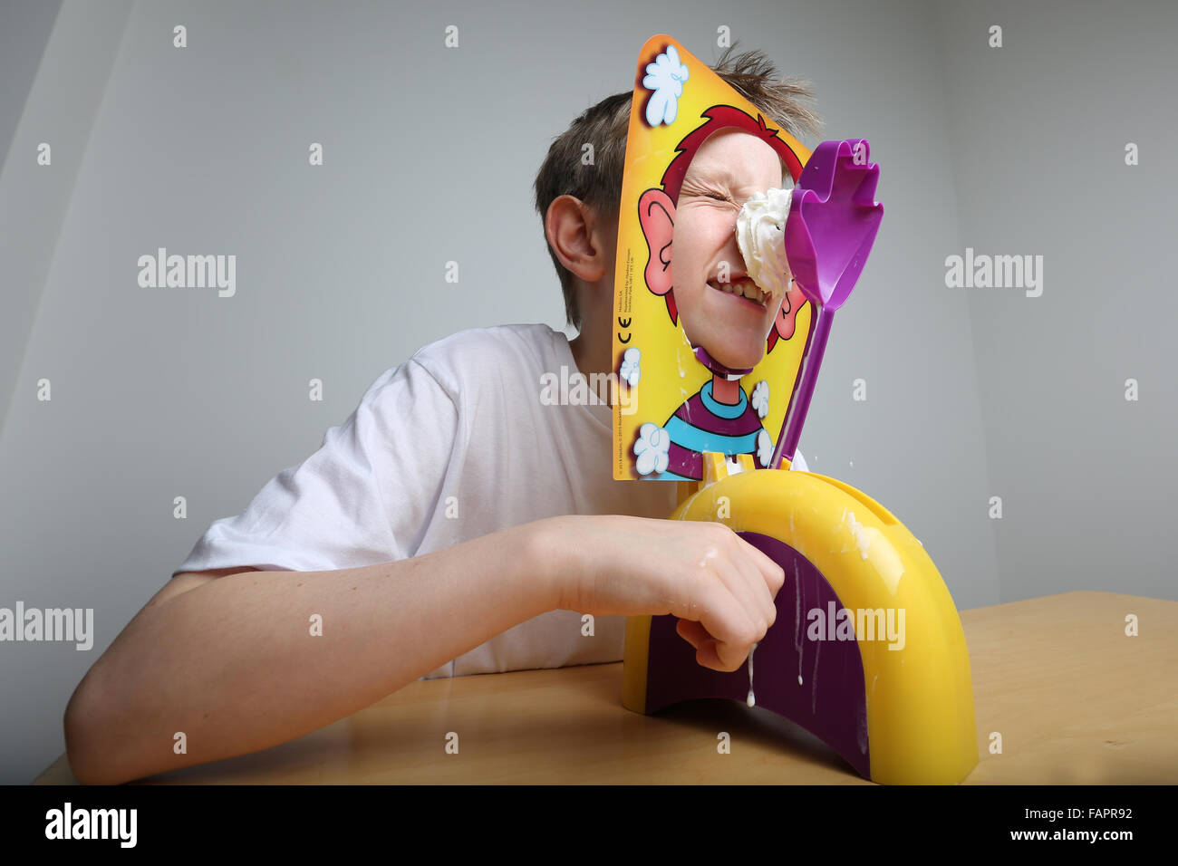 Un garçon jouant le jeu de Pie visage par Hasbro obtenir couverts en crème Banque D'Images
