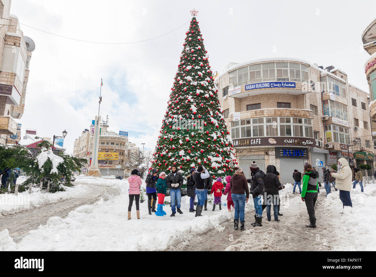 Les gens debout autour d'un arbre de Noël dans la neige à Ramallah, Palestine Banque D'Images