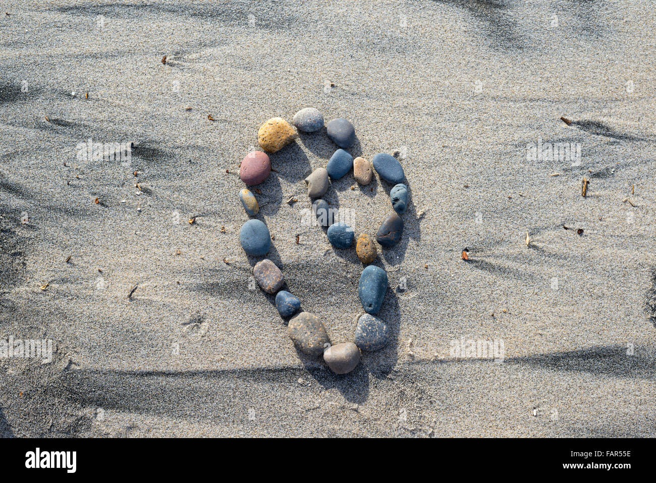 Forme de coeur formé par des pierres sur le sable. Banque D'Images