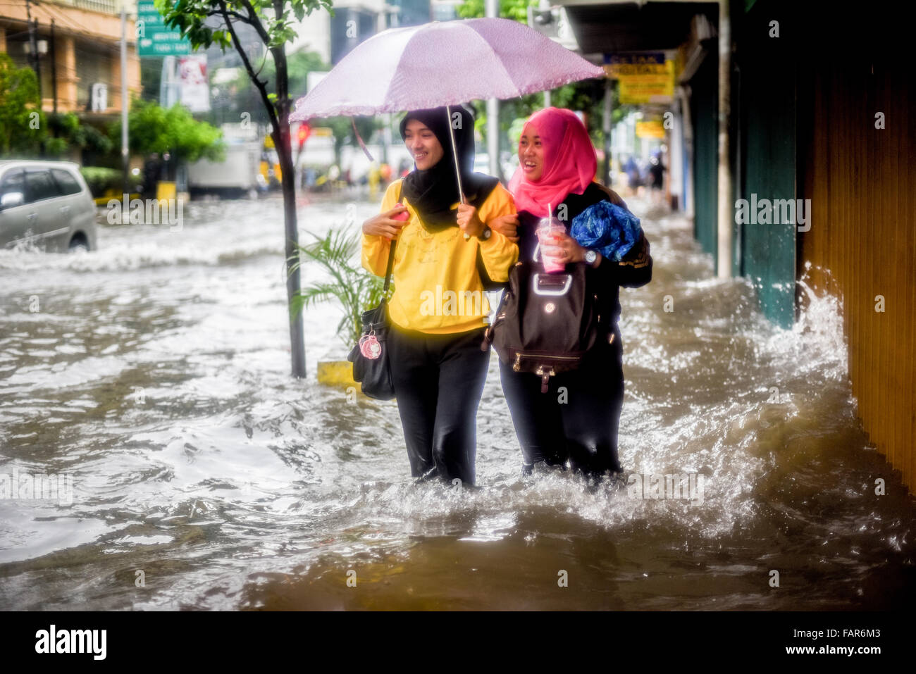 Des femmes marchant sur une passerelle inondée à Jakarta, après une pluie continue ont quitté le centre-ville de la capitale indonésienne inondé. Banque D'Images