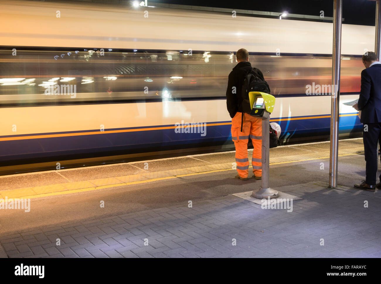 Workman attendant le train sur la plate-forme de la gare. ROYAUME-UNI Banque D'Images