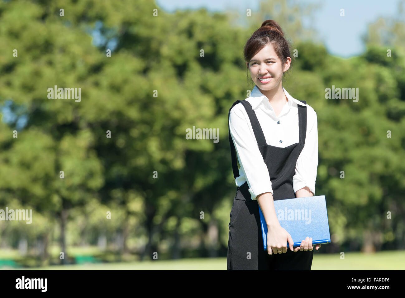 Asian student holding books et souriant alors qu'il se trouvait en position de stationnement au college Banque D'Images