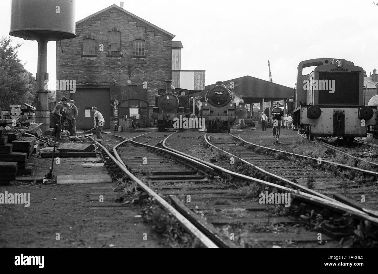 La gare de Haworth, dans le Yorkshire de l'Ouest vers 1982 Photographie noir et blanc image d'archive. Accueil de la Concon et chemin de fer de la vallée d'une valeur, le KWVR est assuré par des bénévoles. Cour avec des moteurs à vapeur, de travail, de la protection moteur tour d'eau, pistes, points et un véhicule rail-route. Banque D'Images