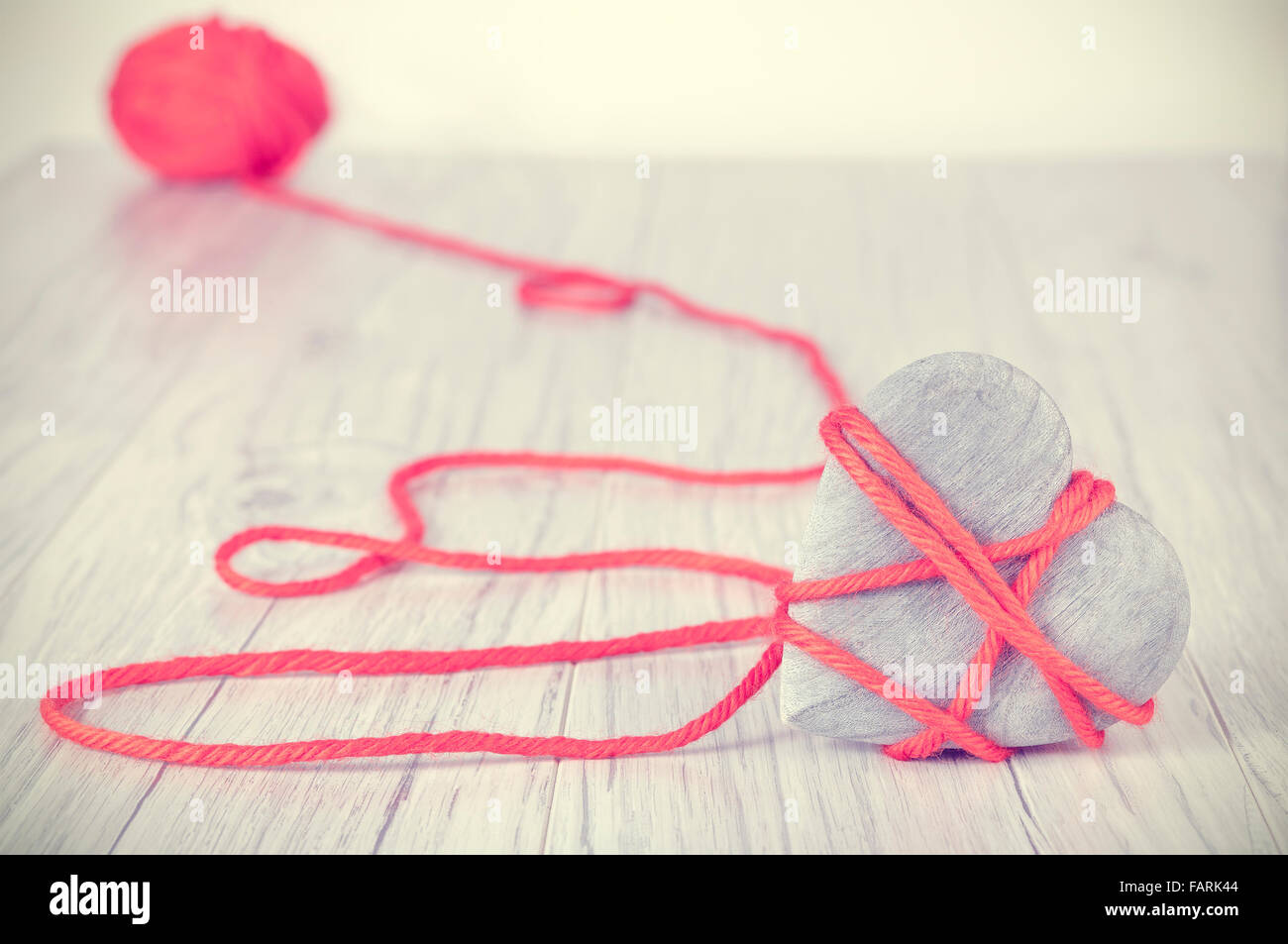 Coeur en bois aux couleurs rétro attaché avec du fil rouge, concept photo. Banque D'Images