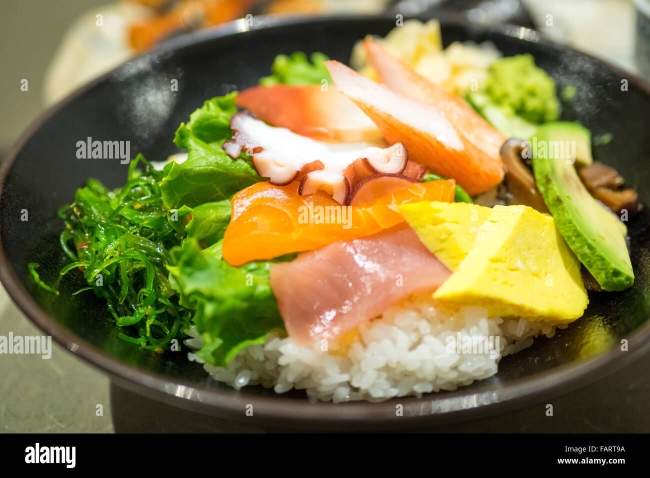 Un bol de chirashi (chirashizushi), qui se compose de riz sushi surmonté d'une variété de poisson cru et de légumes. Banque D'Images