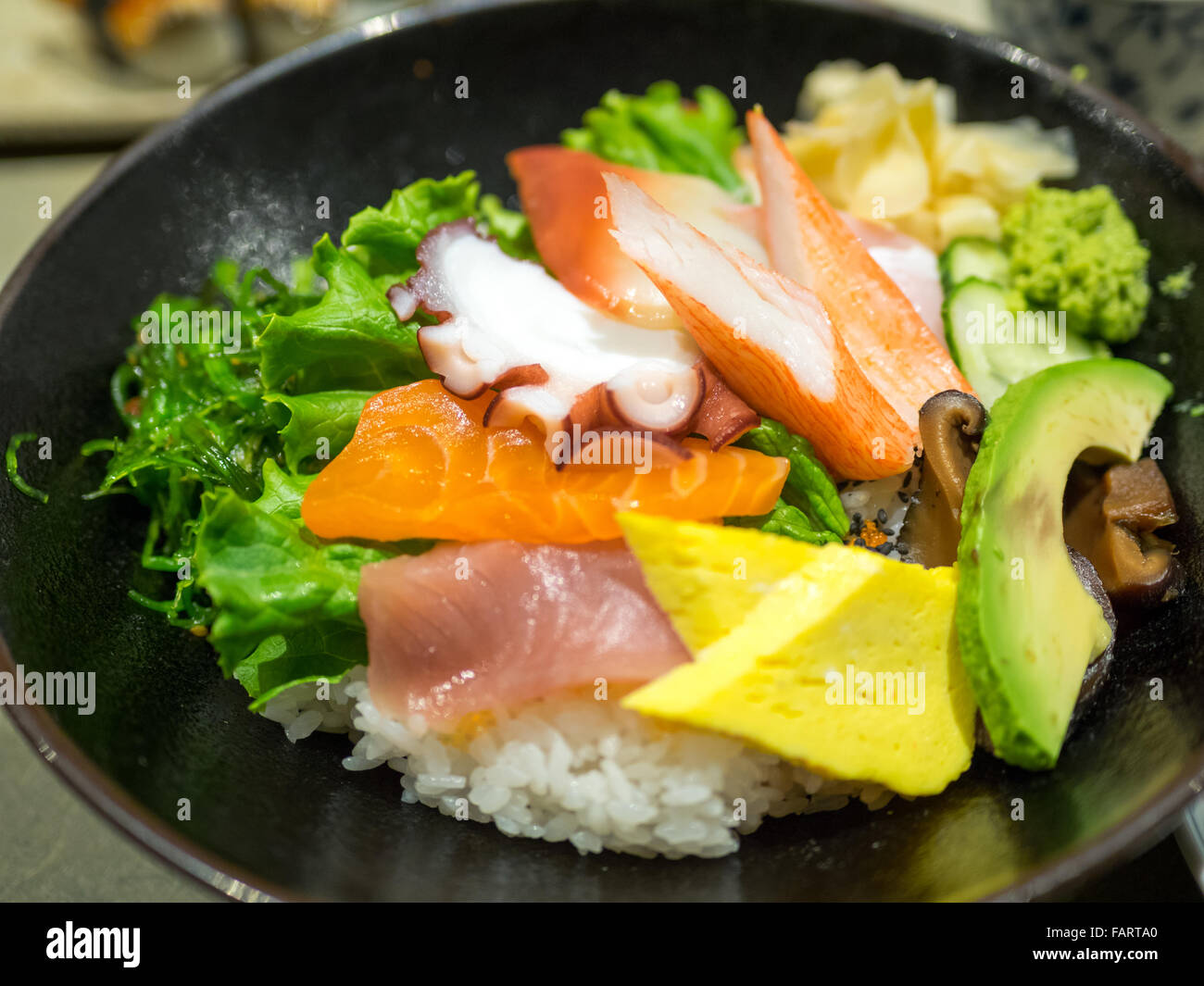 Un bol de chirashi (chirashizushi), qui se compose de riz sushi surmonté d'une variété de poisson cru et de légumes. Banque D'Images