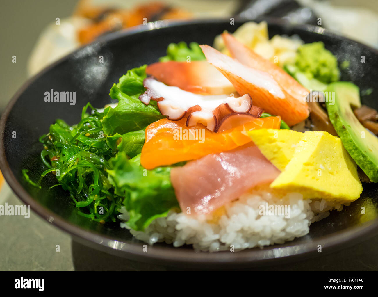Un bol de chirashi (chirashizushi), qui se compose de riz sushi surmonté d'une variété de poisson cru et de légumes. Banque D'Images