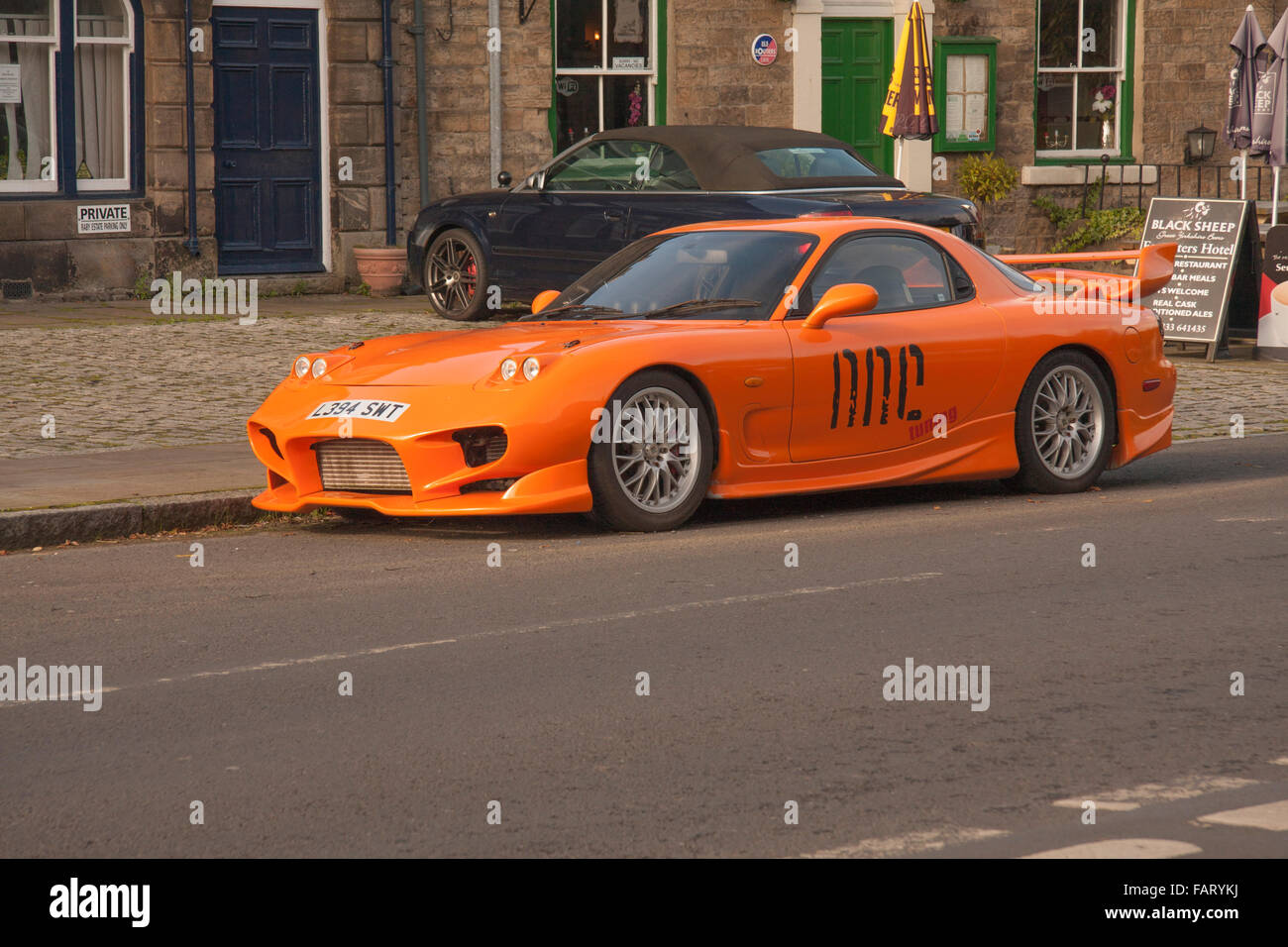 Mazda RX7 de couleur orange sports voiture garée à l'extérieur de librairie dans le village de Middleton-in-Teesdale,fr,Durham Angleterre Banque D'Images