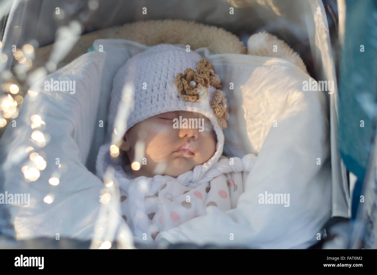 Un mignon petit bébé dort sous l'imperméable dans la perambulator Banque D'Images