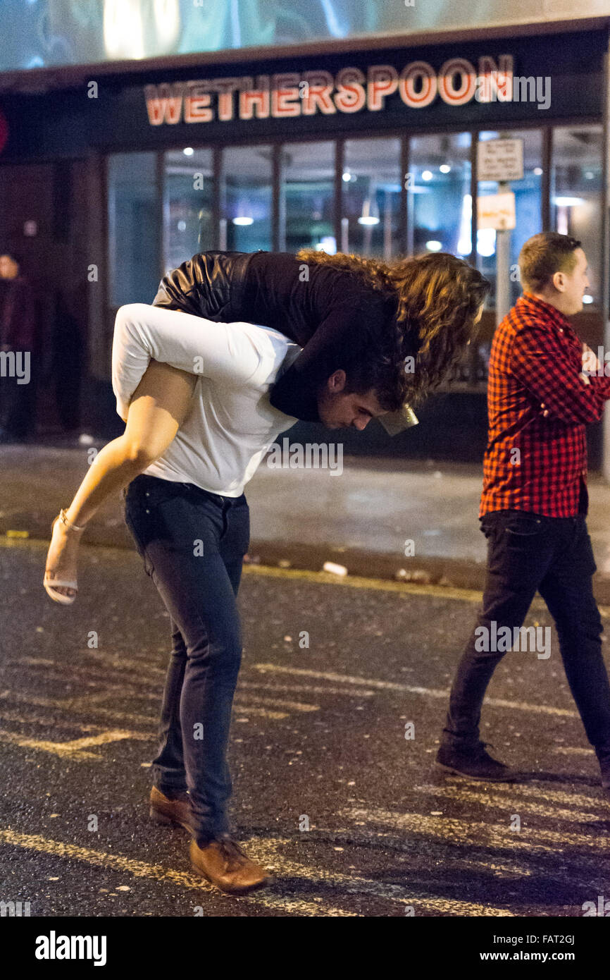 Sur la photo : un homme donne à une femme un piggy back. Re : New Year's Eve à Cardiff, Pays de Galles, Royaume-Uni. Premières heures du vendredi 1er janvier 20 Banque D'Images