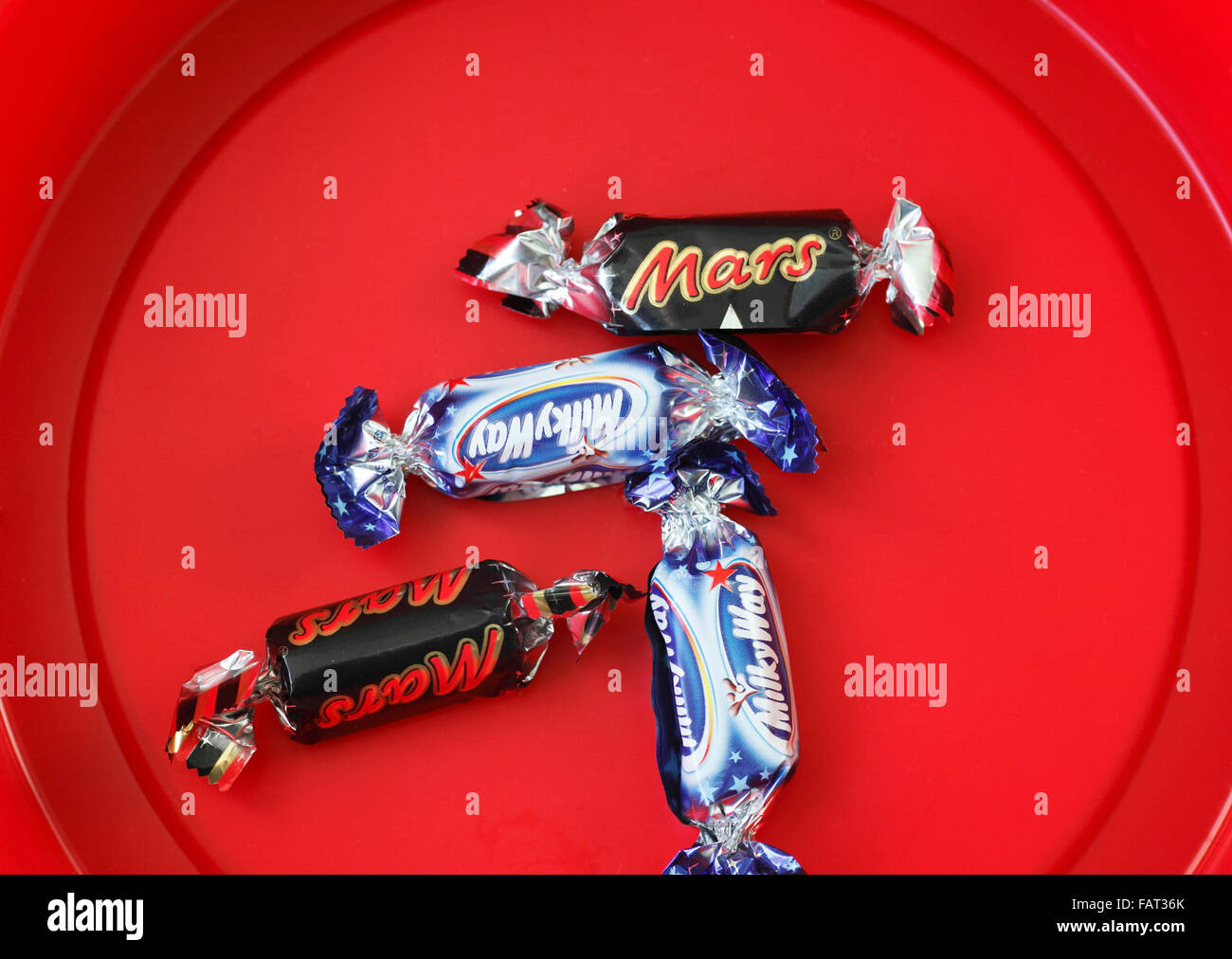 Voie lactée et Mars fun size bars à gauche dans le fond d'un remous de chocolats. Banque D'Images