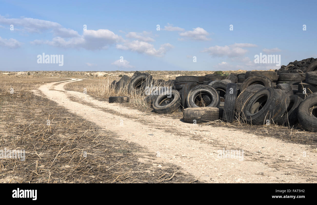 Vieux pneus en caoutchouc utilisé dans un chantier de recyclage empilés en attente d'être déchiquetés et reconditionnées en produits utilisables Banque D'Images