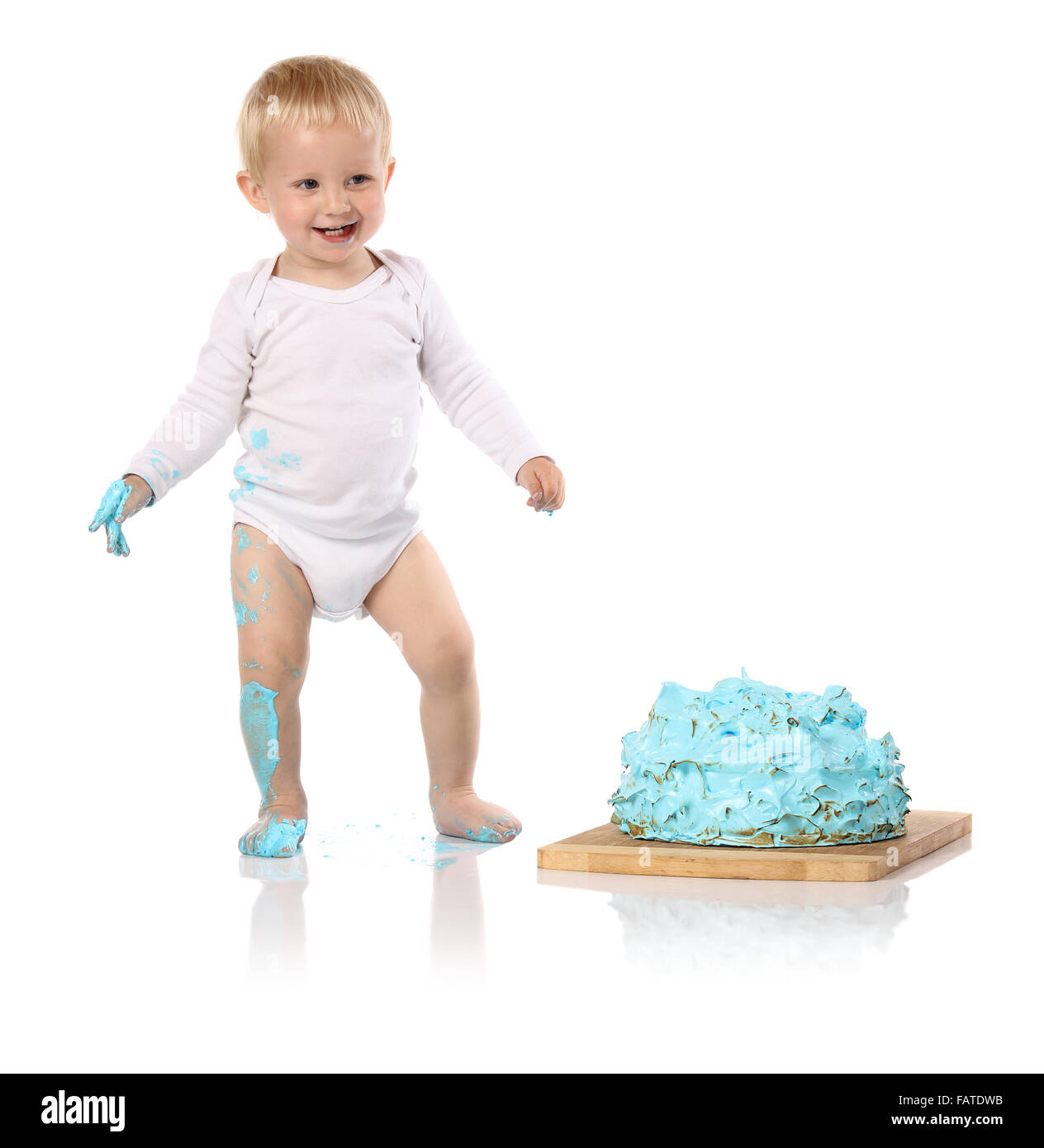 Un petit garçon âgé d'un an brisant une anniversaire glacé bleu gâteau sur une planche de bois. L'image est isolé sur un fond blanc. Banque D'Images