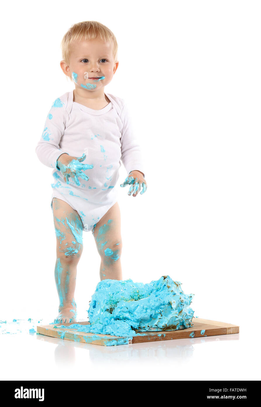 Un petit garçon âgé d'un an brisant une anniversaire glacé bleu gâteau sur une planche de bois. L'image est isolé sur un fond blanc. Banque D'Images