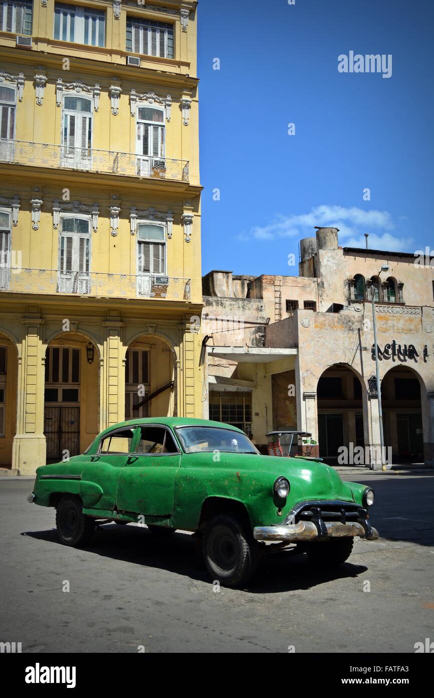 Beat up old vintage verte voiture garée dans un square ensoleillé dans la Vieille Havane, Cuba, entouré de bâtiments de style colonial Banque D'Images