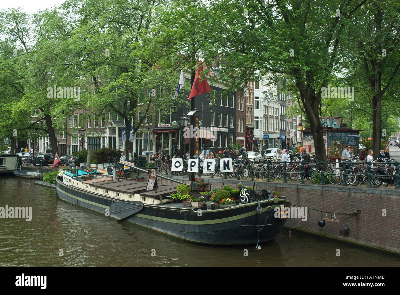 La vieille ville d'Amsterdam, Hollande. House boat / Musée Barge sur un canal et scène de rue avec des vélos et des arbres. Banque D'Images