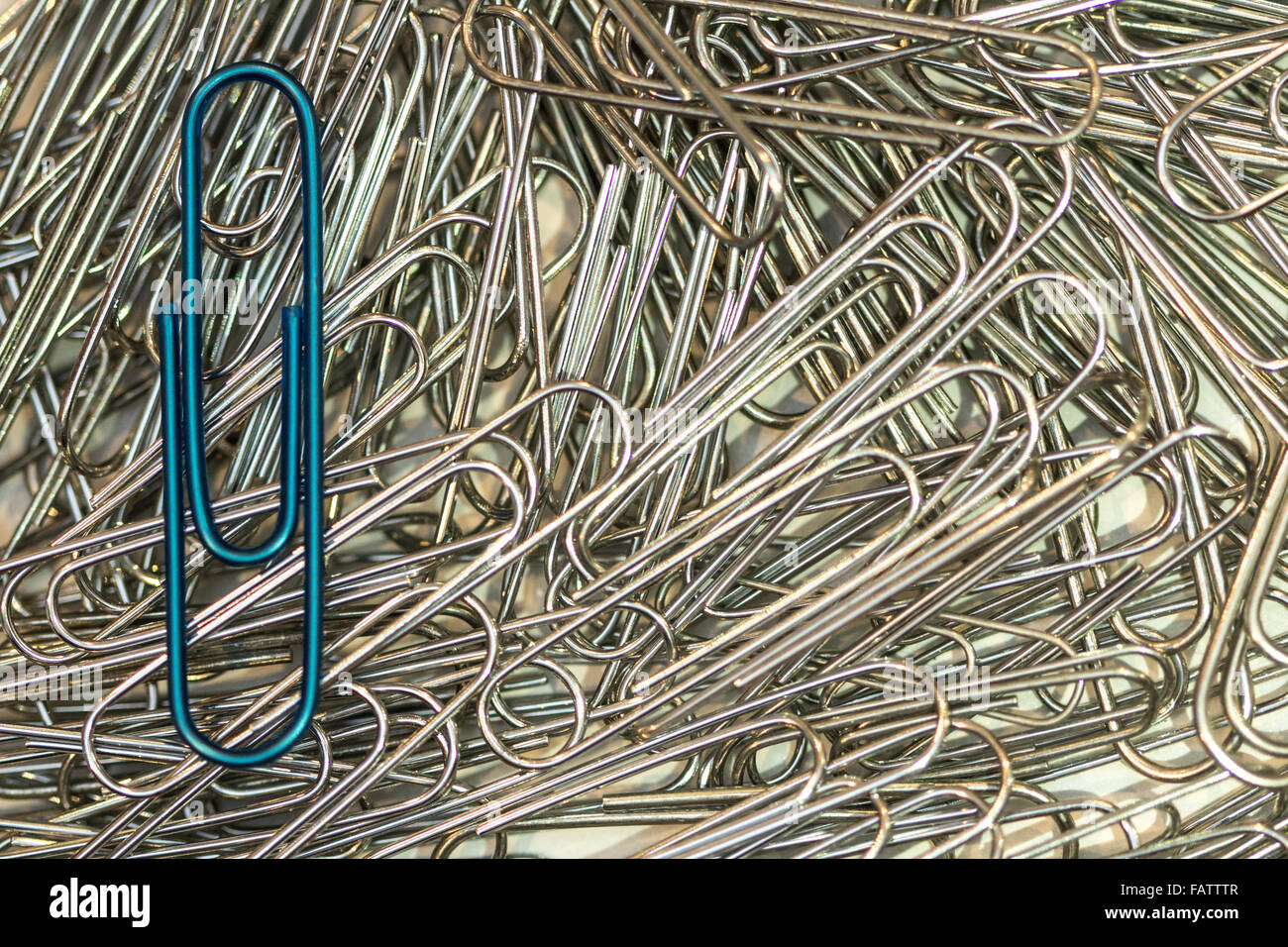 Trombone bleu métallique qui met sur une pile de papier argenté clips Banque D'Images