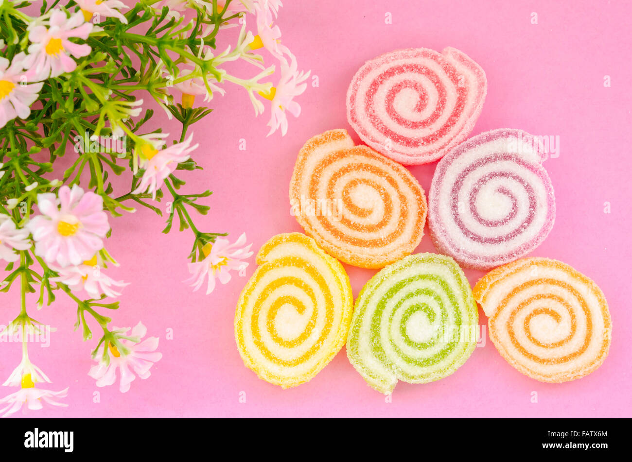 Saveur douce, gelée de fruits, de bonbons colorés dessert avec fleur sur fond rose. Banque D'Images