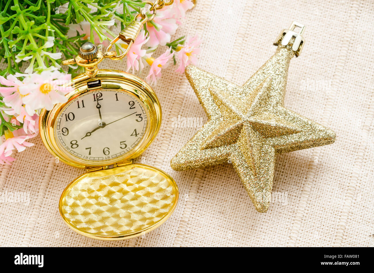 Montre en or et l'étoile d'or Noël avec fleur sur fond de tissu. Banque D'Images