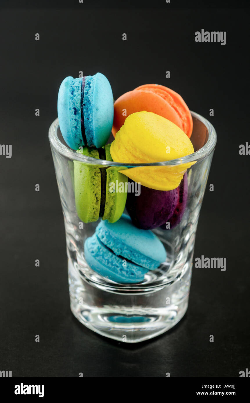 Doux et coloré en verre tasse macarons français sur un fond noir. Banque D'Images